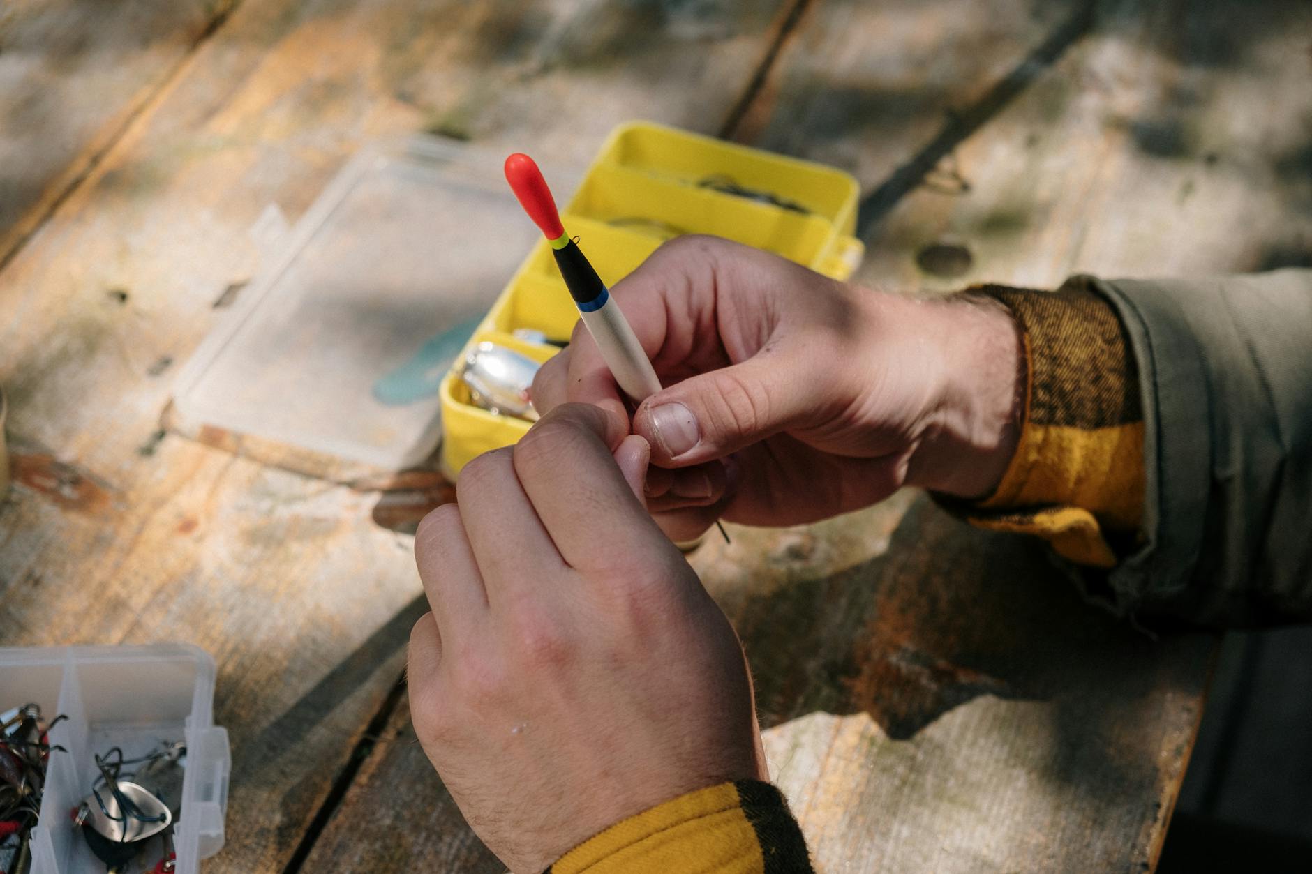 Ręce przygotowujące zestaw wędkarski z przynętami i haczykami na drewnie