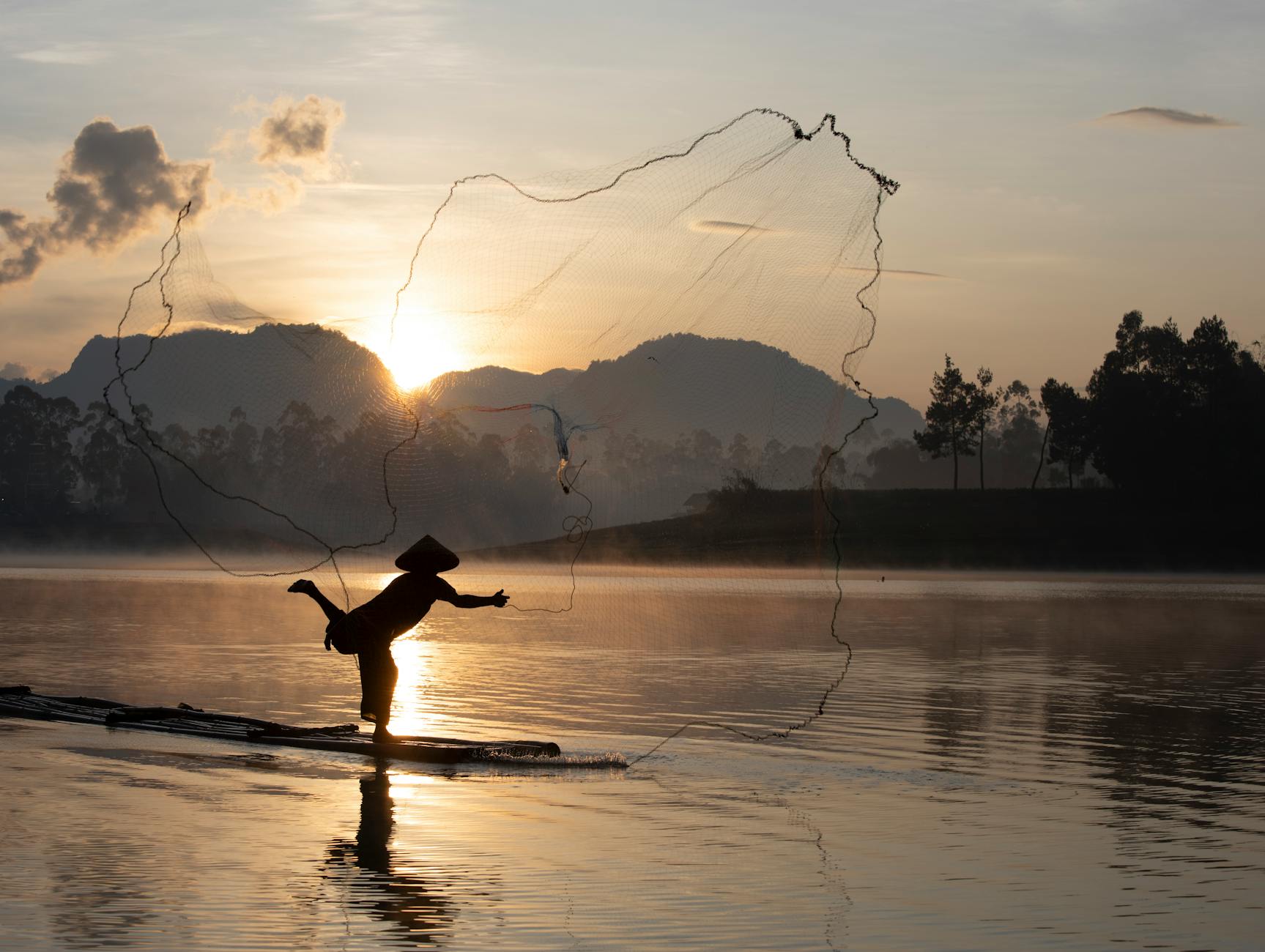 Wędkarz w małej łodzi na spokojnej wodzie o świcie