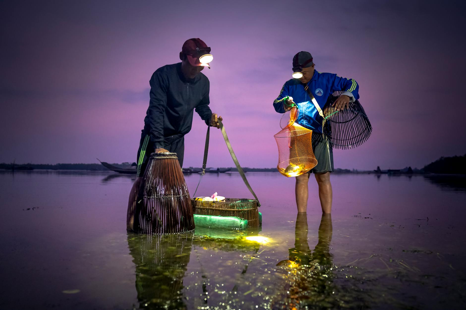 Wędkarze nocą w wodzie, latarki czołowe oświetlają sprzęt