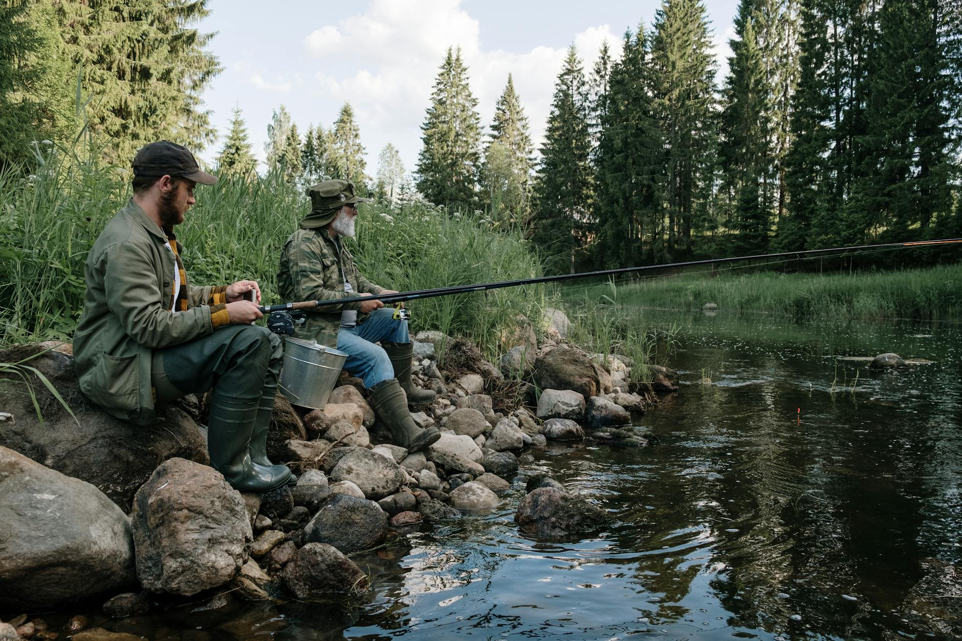 Dwóch wędkarzy ze spinningami nad leśną rzeką