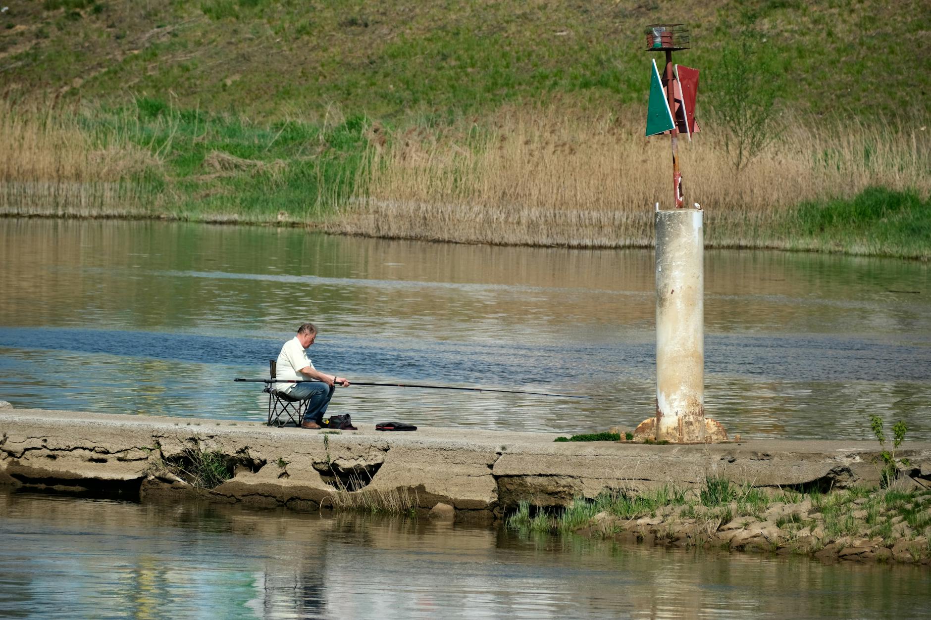 Wędkarz spinningowy nad spokojną rzeką w słoneczny wiosenny dzień